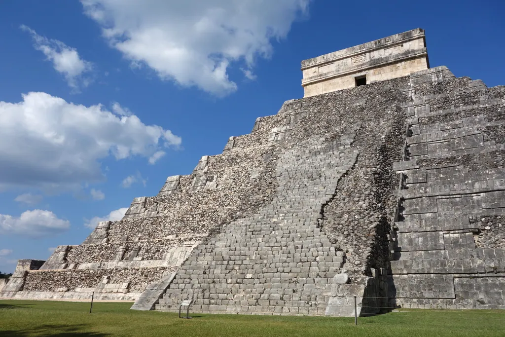 The Temple of Kukulcán at Chichén Itzá under a blue sky with white clouds
