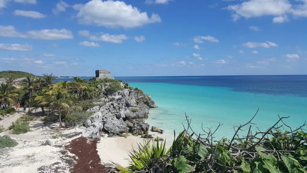 Mayan ruins on a rocky clifftop above a white sand beach and turquoise sea at Tulum
