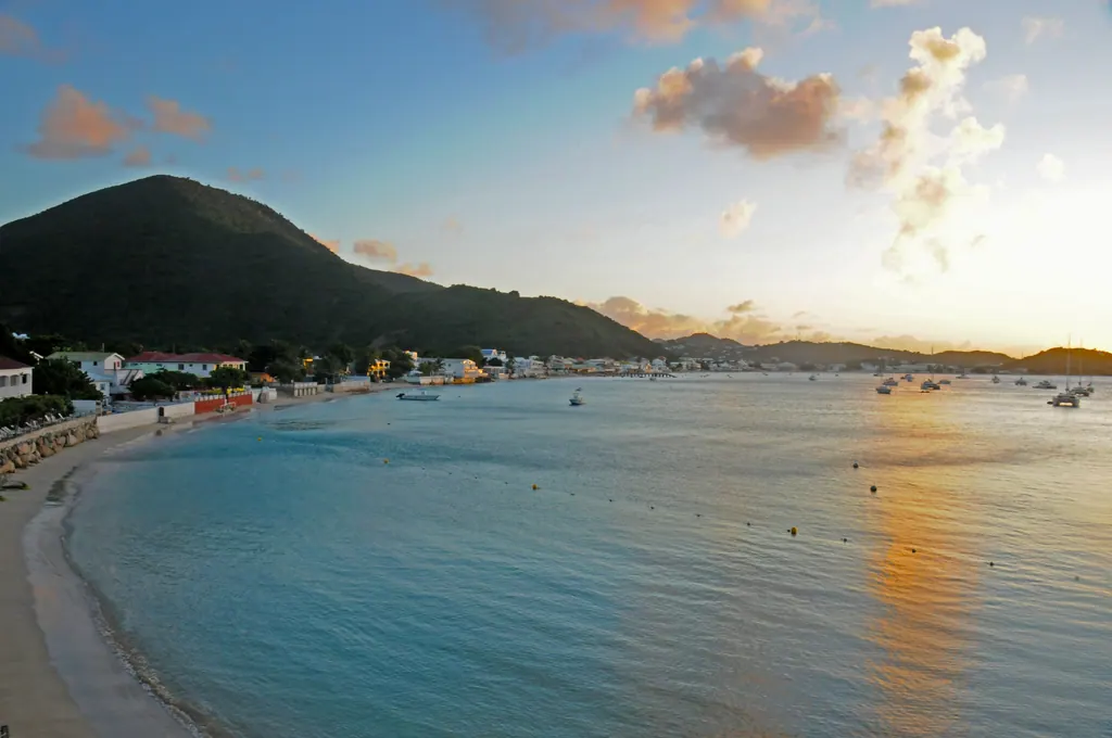 Calm turquoise water and the curving shoreline of Grand Case Bay on Saint Martin under a late afternoon sky